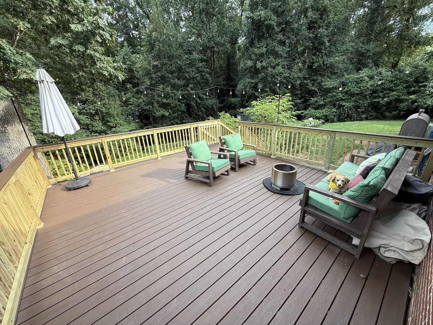 A newly built composite deck with railings, outdoor chairs, and a fire table
